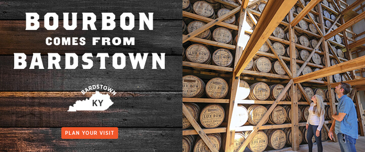 White couple looking up at bourbon barrel rack with the text Bourbon Comes From Bardstown